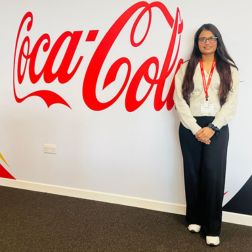 student standing at a wall with the Coca Cola logoi